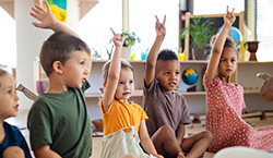 children-sitting-in-classroom-raising-hands